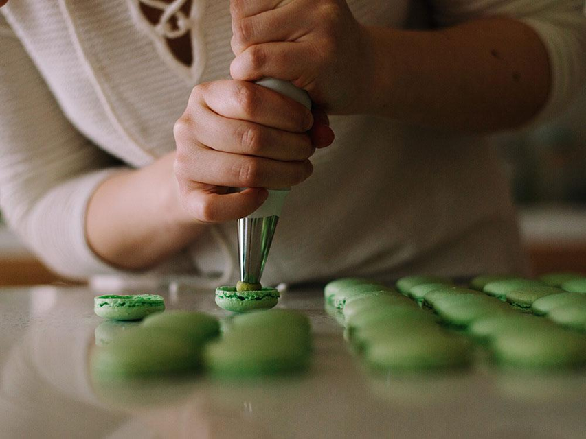 Chef is filling green macarons with cream